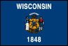 Image of the Wisconsin State Flag.  The flag consists of a dark blue field with the state coat of arms centered on each side. The word 'WISCONSIN' appears in white Gothic letters above the state coat of arms and the date that Wisconsin was admitted to the union, '1848' is in white Gothic letters below the state coat of arms. Above a shield within the coat of arms is the state motto 'Forward' in black letters on a white ribbon. Below that, but also above the shield, is a badger, the state animal. On opposite sides of the shield, a sailor and miner symbolize the type of work that people did in 1863, at the time the flag was made. The shield in the center shows Wisconsin's support for the United States. In four quadrants of the shield are representations of the important trades of the times: agriculture (plow), mining (pick and shovel), manufacturing (arm and hammer) and navigation (anchor). At the base of the shield is a cornucopia, or horn of plenty, standing for prosperity and abundance, while a pyramid of 13 lead ingots represents mineral wealth and the 13 original U.S. states. In the center of the shield lies the U.S. Coat of Arms, symbolizing Wisconsins loyalty to the Union. All of the symbols on the flag represent a richness in natural resources, including the lakes and waterways, mineral riches under ground which provide useful products, and rich soil which provides abundance in crop production and food for people. The flag was adopted in 1863 and amended in 1979.